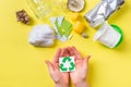 Recycle sign in child hands, clean trash metal, plastic paper and glass. Recycling concept on yellow Royalty Free Stock Photo