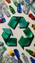 Recycle sign made out of sturdy plastic surrounded by a variety of empty plastic bottles of different shapes sizes and colors