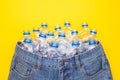 Recycle technology of plastic bottle to make clothes. Top view old water bottle and blue short jeans on yellow