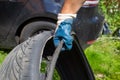 Recycle of wheels. the hand of the master in a blue glove holds the torn tire. on the background black car in blur.