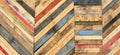 A variety of colored recycled wooden pallets cut and arranged in a herringbone pattern