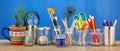 Recycled jars, tin and mug reused for different contents on wooden bench, blue background