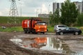 A Recycling Company garbage truck drives around a puddle near parked cars in a residential neighborhood on a cloudy summer day Royalty Free Stock Photo