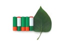 Recycling, energy, environment and ecology concept - close up of green alkaline batteries with leaf over white background