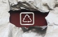 Recycling icon symbol in silver on dark red under torn foil paper. Eco healthy living reuse reduce concept