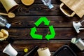 Recycling symbol and different garbage, paper bag, cup, flatware, plastic bottle for ecology wooden background top view Royalty Free Stock Photo