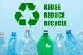 Recycling symbol with recycle reduce reuse words and empty plastic bottles on blue background Royalty Free Stock Photo