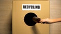 Recycling word written on cardboard box, people hands throwing reusable trash