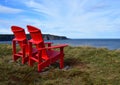 Red Adirondack chairs on the edge of a cliff overlooking the ocean Royalty Free Stock Photo