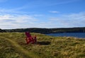 Red Adirondack chairs on the edge of a cliff overlooking the ocean Royalty Free Stock Photo