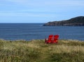 Red Adirondack chairs on the edge of a cliff overlooking the ocean Royalty Free Stock Photo