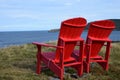 Red Adirondack chairs on the edge of a cliff overlooking the ocean Royalty Free Stock Photo