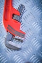 Red adjustable monkey wrench on corrugated metallic background c