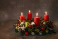 Red advent candles on a wreath with Christmas decoration against a dark warm background with bokeh lights, copy space, selected Royalty Free Stock Photo