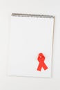 Red aids ribbon on open notebook Royalty Free Stock Photo