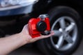 Red air horn for a car on men`s hand before a modern black car. Electric Car air horn. Royalty Free Stock Photo