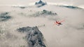 Red airplane flying over snow mountains with pine trees in the clouds. Royalty Free Stock Photo