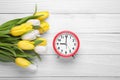 Red alarm clock and beautiful tulips on white wooden table, flat lay with space for text. Spring time Royalty Free Stock Photo