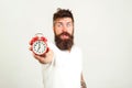 Red alarm clock and blurred man on white background. Deadline concept with shocked bearded man holding alarm clock. Brutal