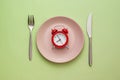 Red alarm clock on a clean pink plate