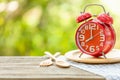 Red alarm clock, Fork, and spoon on wooden table with green outdoor nature blur background. Eight o'clock, Time for eating concep Royalty Free Stock Photo