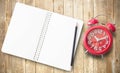 Red alarm clock and note book on brown wooden Royalty Free Stock Photo