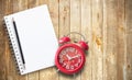 Red alarm clock and note book on brown wooden Royalty Free Stock Photo