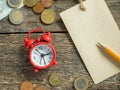 Red alarm clock Notepad for writing pencil Euro Money coins on wooden rustic table Royalty Free Stock Photo