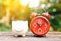 Red alarm clock with piggy bank on old wood Royalty Free Stock Photo