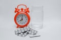 Red alarm clock and pills in a blister, glass Royalty Free Stock Photo