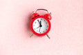 Red alarm clock on pink glitter background. Royalty Free Stock Photo