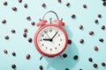 Red alarm clock and roasted coffee beans on blue background with shadow. Concept of morning awakening, beginning of working day Royalty Free Stock Photo