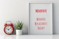 A red alarm clock sitting next to a poster, text Menopause, Hormone Replacement Therapy. Royalty Free Stock Photo