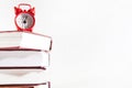 Red alarm clock and a stack of books