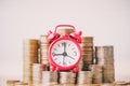 Red alarm clock on stack of coins in concept of savings and money growing or energy save. Royalty Free Stock Photo