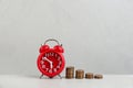 Red alarm clock and stacked coins on grey marble table. Money savings