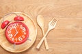 Red alarm clock in wooden dish, spoon and fork on wooden plank b Royalty Free Stock Photo