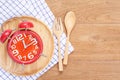 Red alarm clock in wooden dish, spoon and fork on wooden plank b Royalty Free Stock Photo