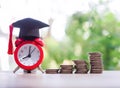 Red alarm with graduation hat and stack of coins, The concept of saving money for education, student loan, scholarship, tuition Royalty Free Stock Photo