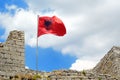 Red Albanian flag with double-headed black eagle waving over wall of Fortress Rozafa near Shkodra city. Fluttering banner with