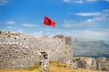 Red Albanian flag with double-headed black eagle waving over wall of Fortress Rozafa near Shkodra city. Fluttering banner with