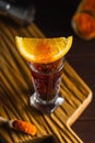 Red alcohol coctail in shot glass with orange slice and ground red hot pepper on wooden board Royalty Free Stock Photo