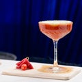 Red alcoholic cocktail in martini glass on blue background, shallow dof Royalty Free Stock Photo