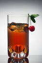 Red alcoholic cocktail in transparent glass with ice and fresh cherry. Gradient background. Royalty Free Stock Photo