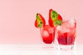 Red alcoholic shots of sweet fruit liquor with ice cubes, strawberry slice, green mint on pastel soft light pink background. Royalty Free Stock Photo