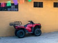 Red all terrain vehicle against yellow wall Royalty Free Stock Photo