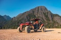 Red, all-terrain vehicle parked in a desert area with a mountain in the background Royalty Free Stock Photo