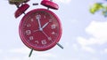 Red analog alarm clock on sky background showing two o\'clock Royalty Free Stock Photo
