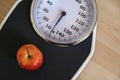 Red apple on an analogue personal scale on a wooden floor, concept for healthy eating, lose weight diet and fitness, high angle