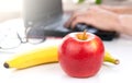 A red apple and banana on the desktop. The concept of a healthy food at work. Close-up. Selective focus